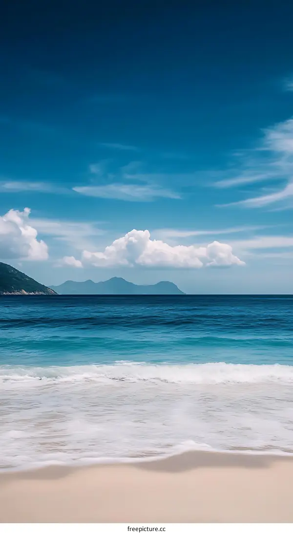 Blue Sky and White Clouds Over Calm Ocean Water and Sandy Beach