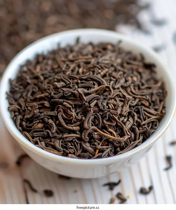 Black Tea Leaves in a White Bowl on a Wooden Surface