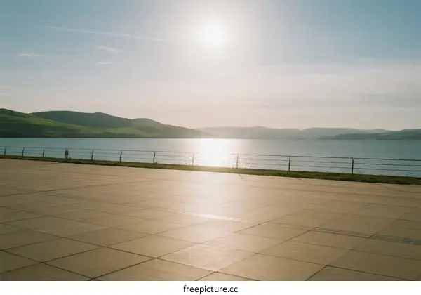 Sunlit Open Area Near Calm Lake with Rolling Hills