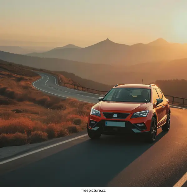 Red SUV on an asphalt road in the mountains at sunset