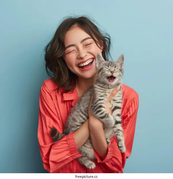 A woman is holding a cat and laughing
