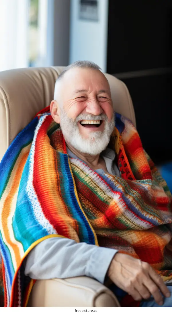 Portrait of a laughing elderly man with a beard wrapped in a blanket