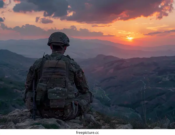 Soldier looking at sunset over mountain range