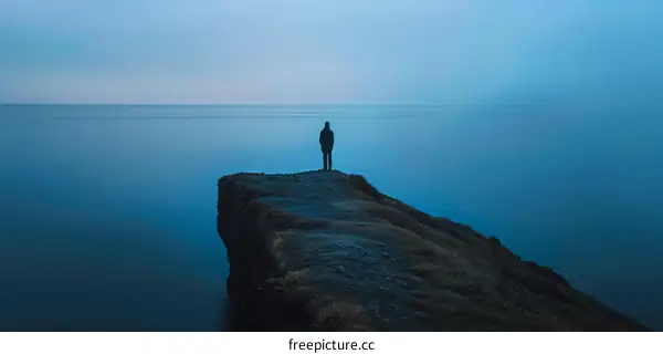 Man standing alone on a cliff overlooking a vast body of water