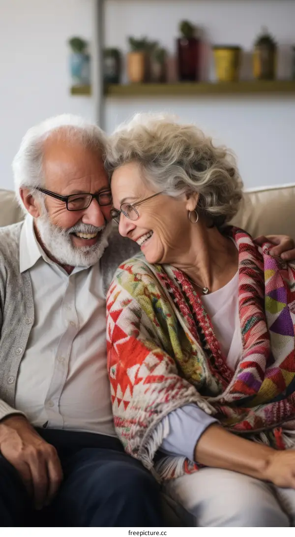 An elderly couple is sitting on a couch and smiling at each other.