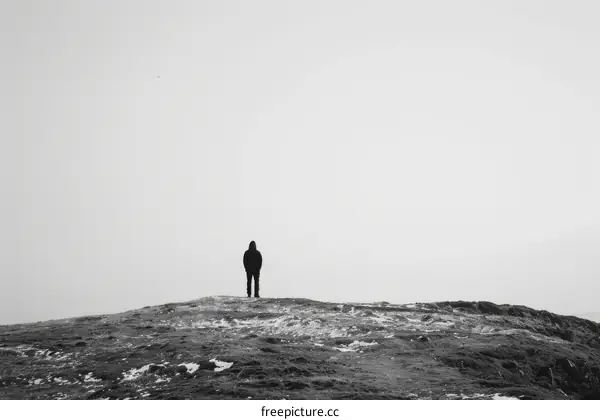 Man standing alone on a hilltop overlooking a vast foggy landscape