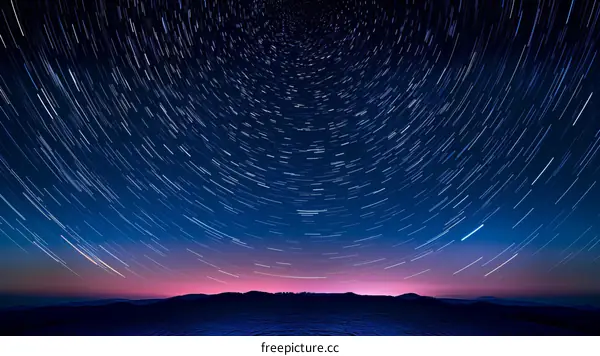 Star trails in the night sky above a mountain range