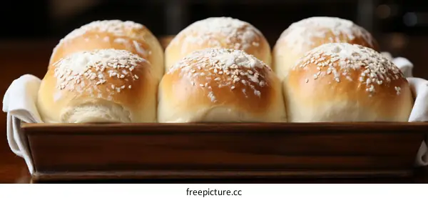 Freshly baked bread rolls with sesame seeds in a wooden basket