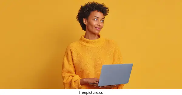 Woman using laptop in yellow sweater