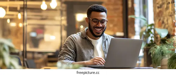Smiling African American Man Working on Laptop in a Cafe