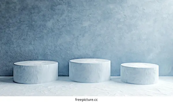 Three Light Blue Cylindrical Pedestals Against a Textured Wall